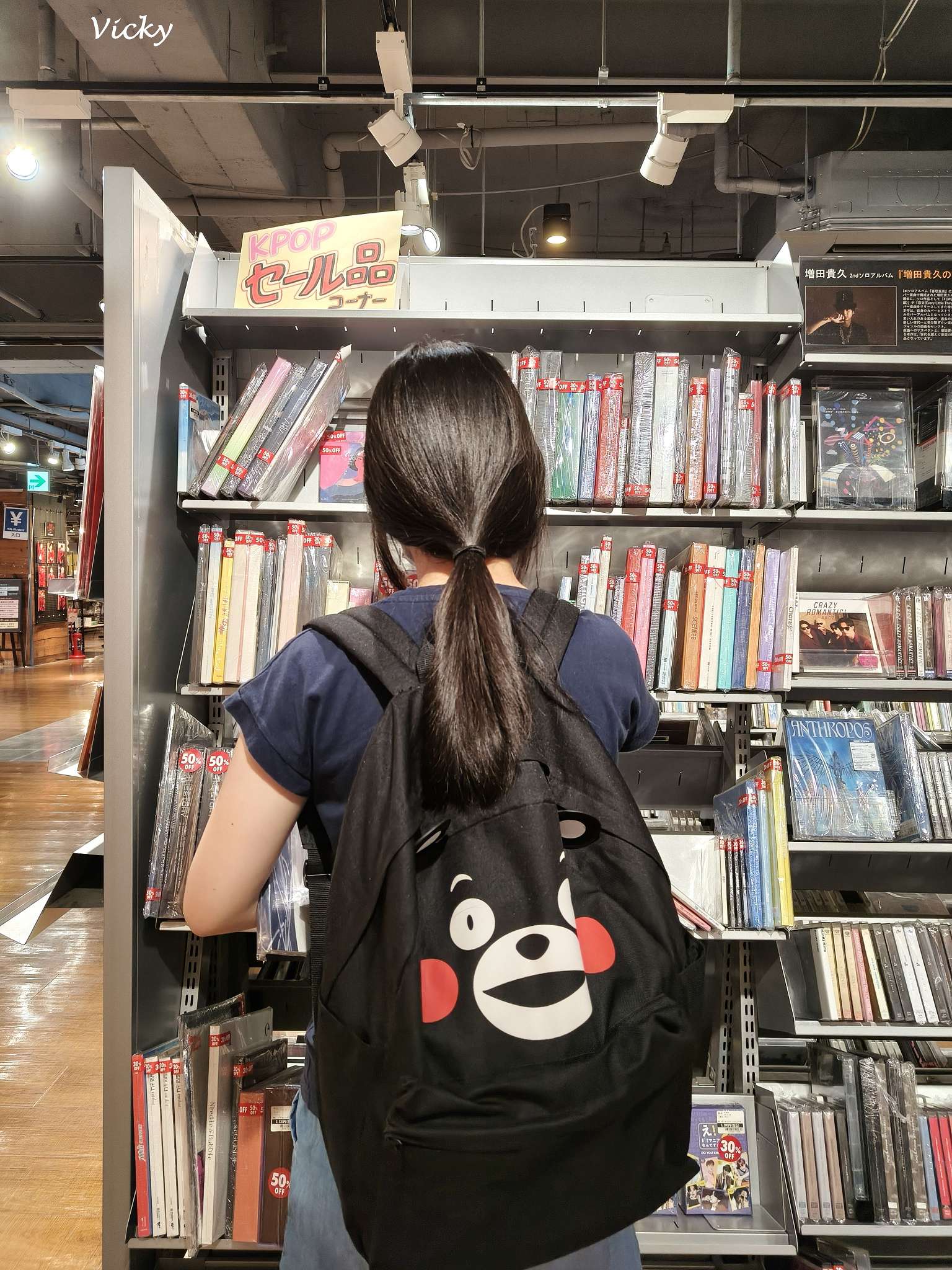 妮妮妹揹著超萌熊本熊後背包在日本蔦屋書店的 KPOP 唱片與特價 CD 專區前挖寶朝聖