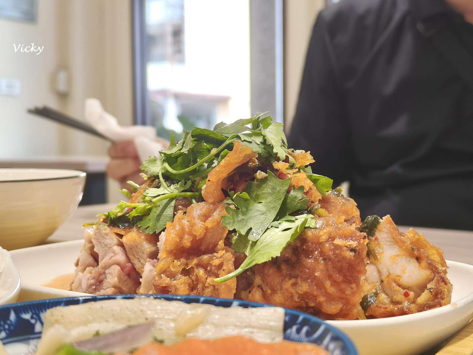 白首定食泰式椒麻去骨雞腿排近照,金黃酥脆的炸雞腿切片堆疊並撒上新鮮香菜