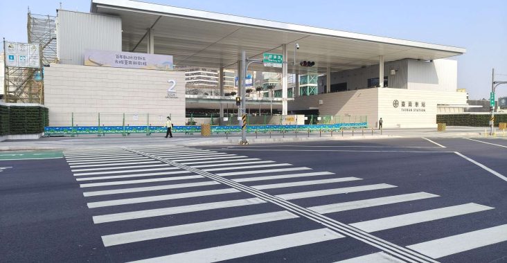 全新落成的台南市區鐵路地下化新站體外觀，牆面掛有「百年軌跡迎新生」標語，展現府城新舊交融的時代意義。